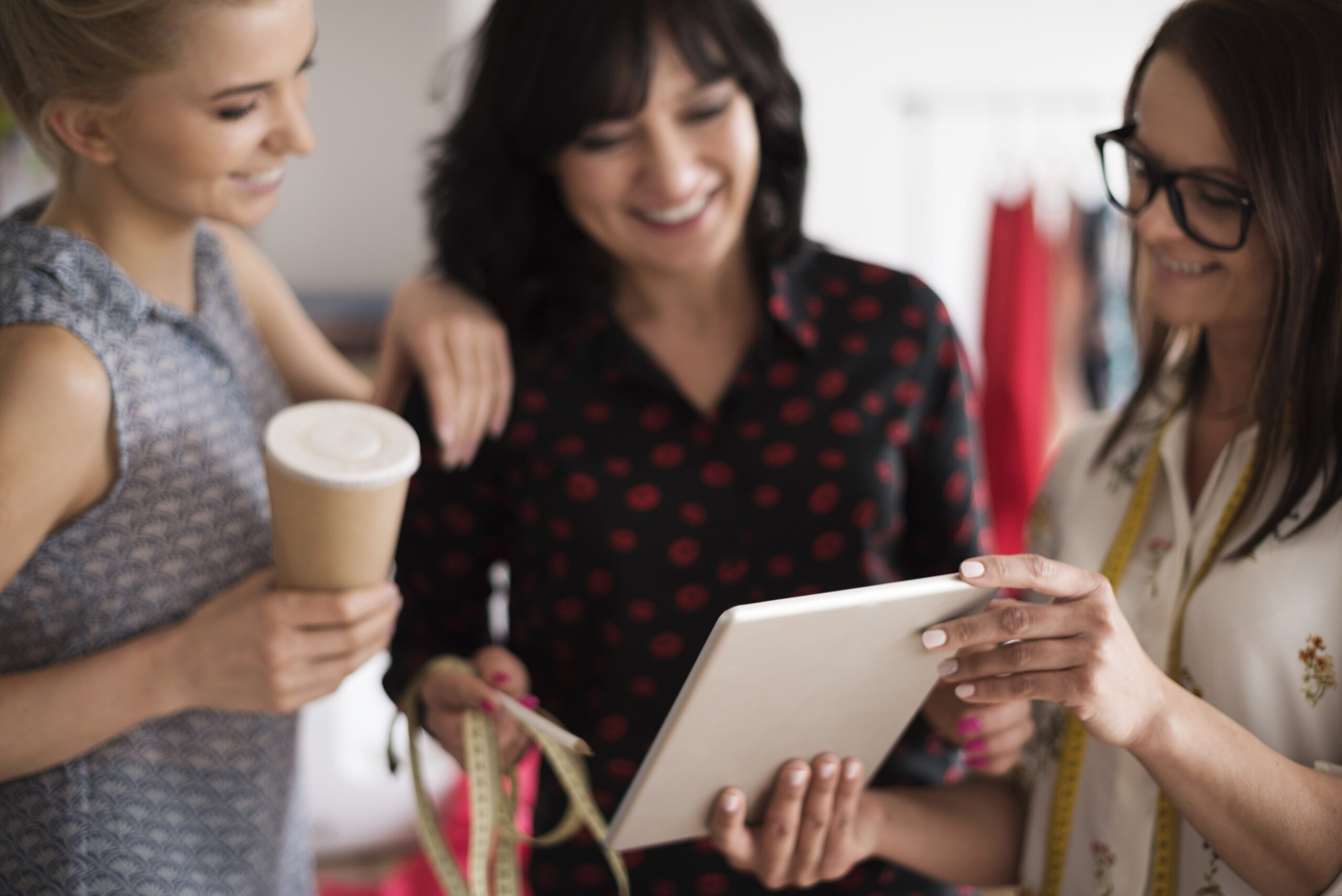 Valle de Calamuchita: la mujer emprendedora. Tres mujeres profesionales colaborando con una tablet y cinta métrica, representando el liderazgo y desarrollo de las emprendedoras en Calamuchita Córdoba para el 8M.